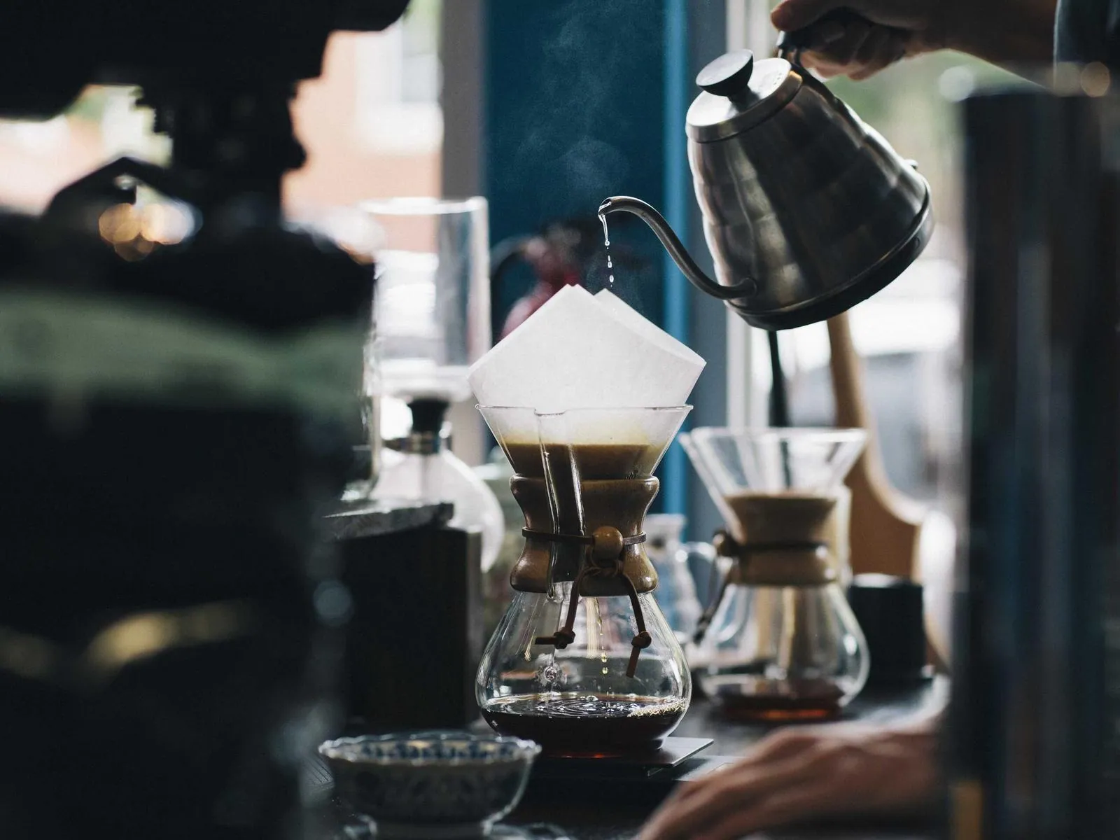 A pour-over coffee set up on a work surface, photographed in low light.