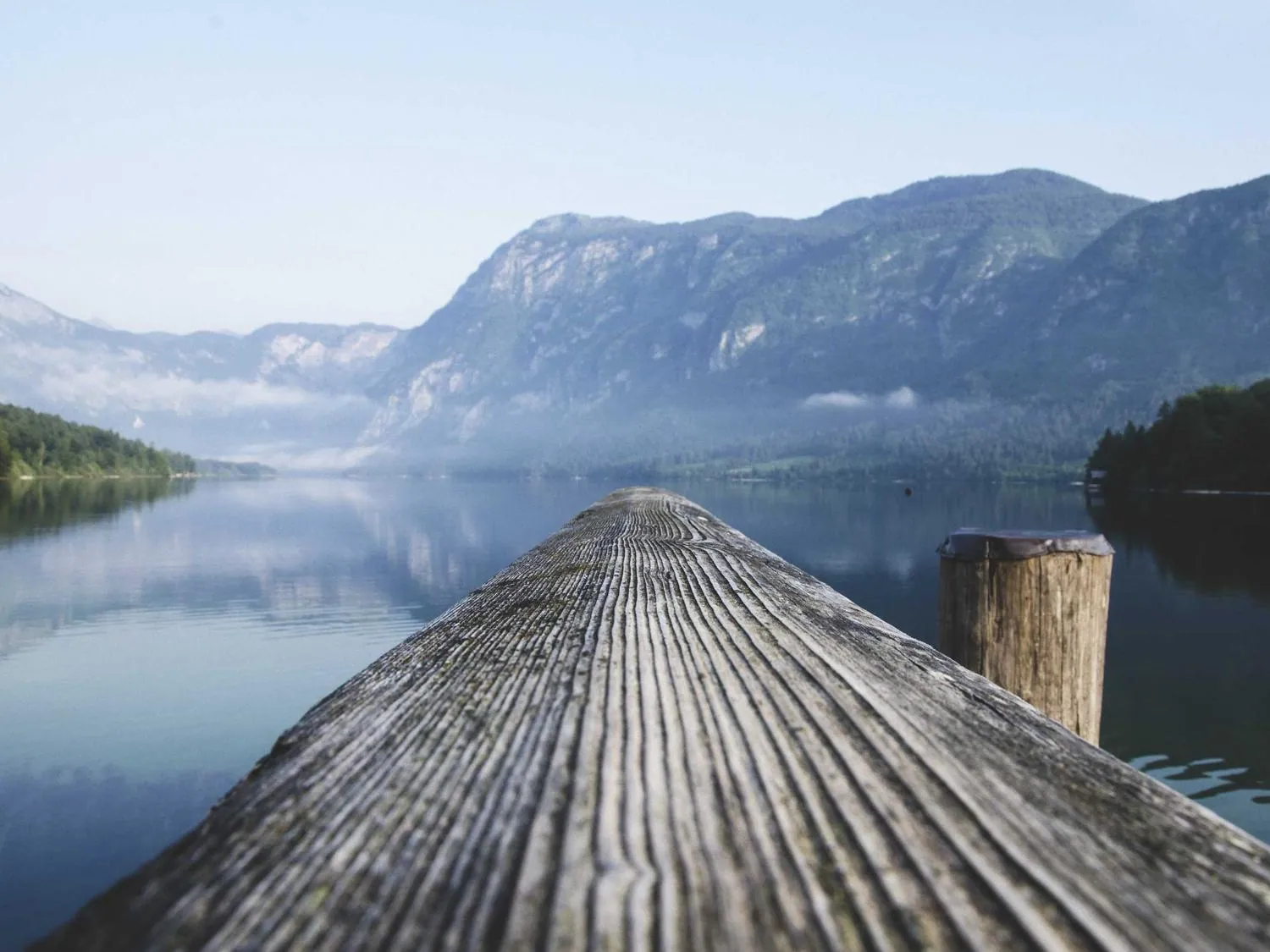 A timber jetty receding into still water.